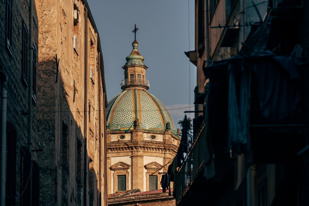 Chiesa del Gesù cupola on sunset seen between old buildings in Palermo, Sicily