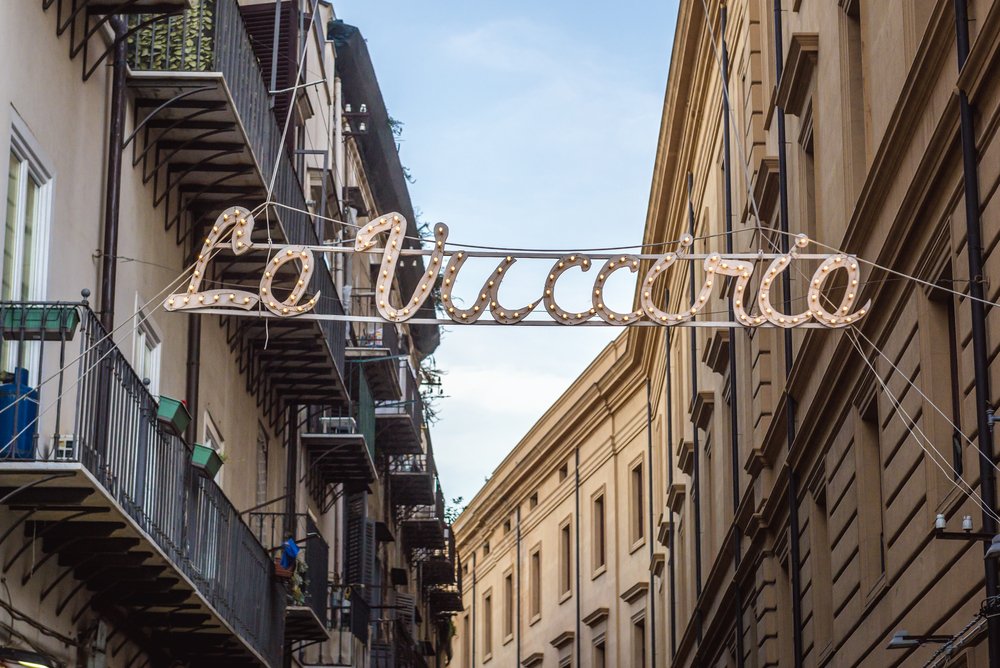 Entrance to street market called La Vucciria in Palermo, Sicily, with a street sign in cursive between two streets