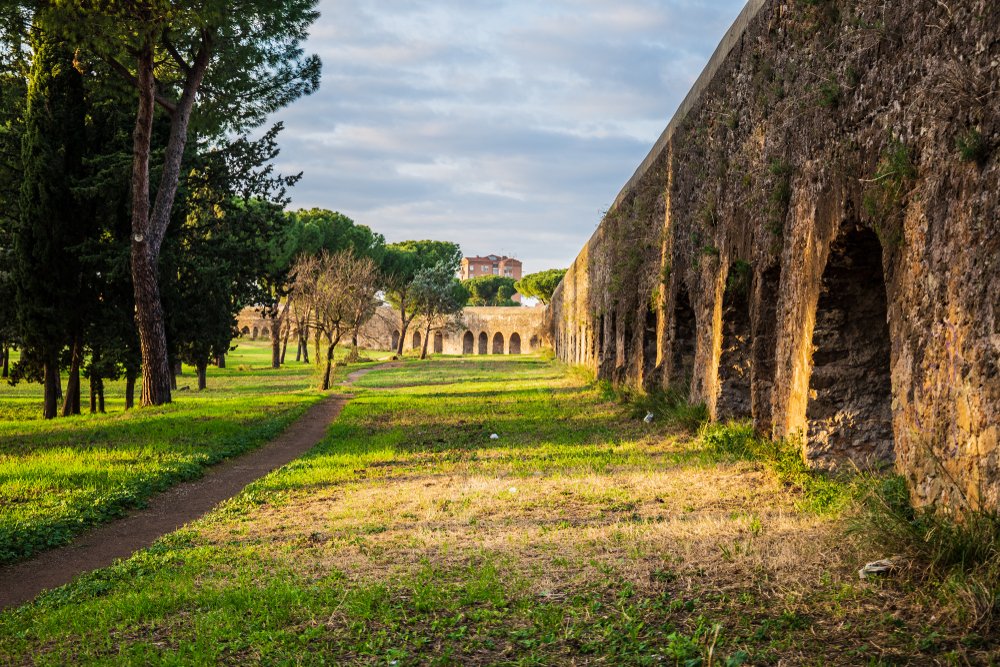 Parco degli Acquedotti at sunset in Rome, Italy with the ancient aqueducts that once carried water into the city of rome now abandoned, with trees and grass around it