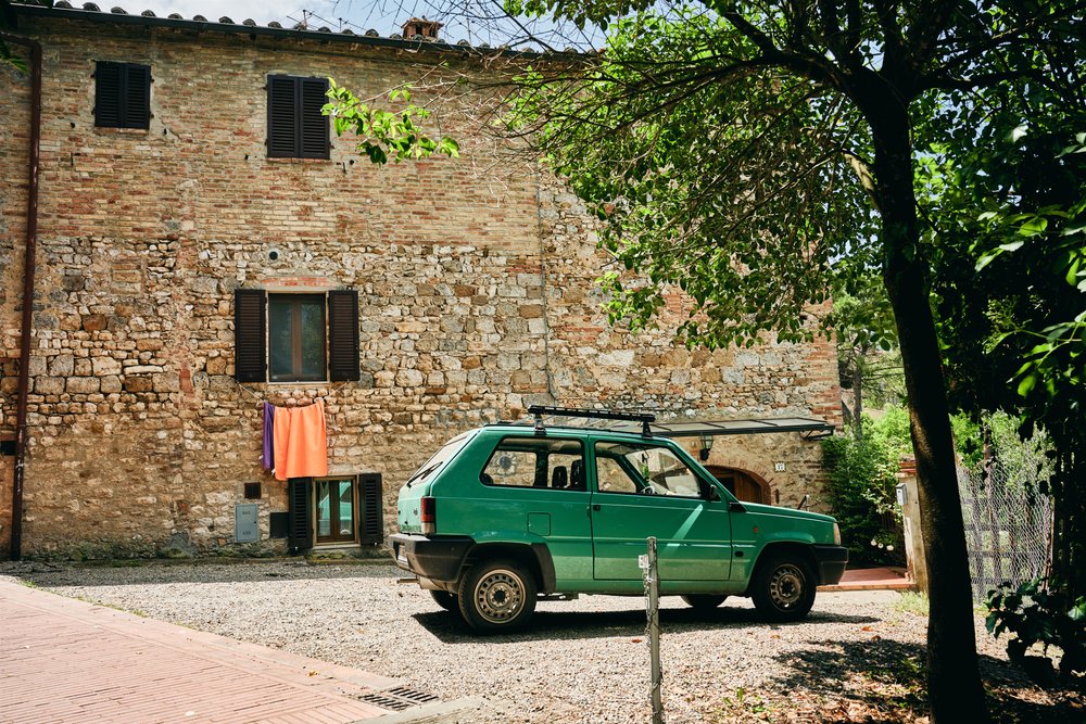 Old-fashioned green car in courtyard of brick house in a typical Italian countryside style village
