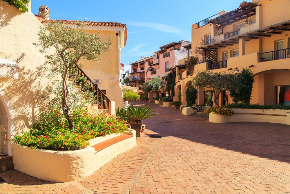 The colorful streets of Porto Cervo, Sardinia, with light-toned architecture and flowers and brick walkway