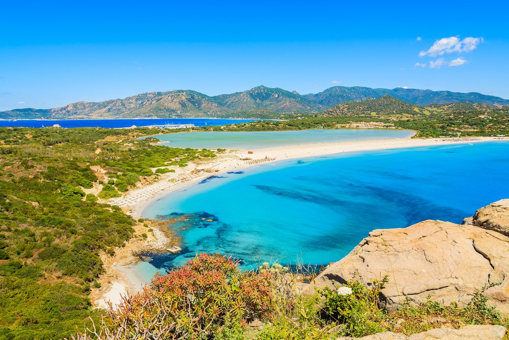 The beautiful crystalline-blue waters of Villasimius with stunning shades of turquoise, dark cerulean, and navy with rugged terrain and sandy white beaches.