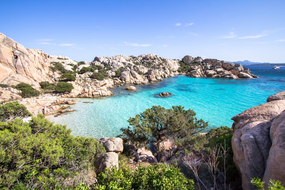 Beach of Cala Coticcio on Caprera island in Sardinia, with crystal clear water, rock formations, and brush