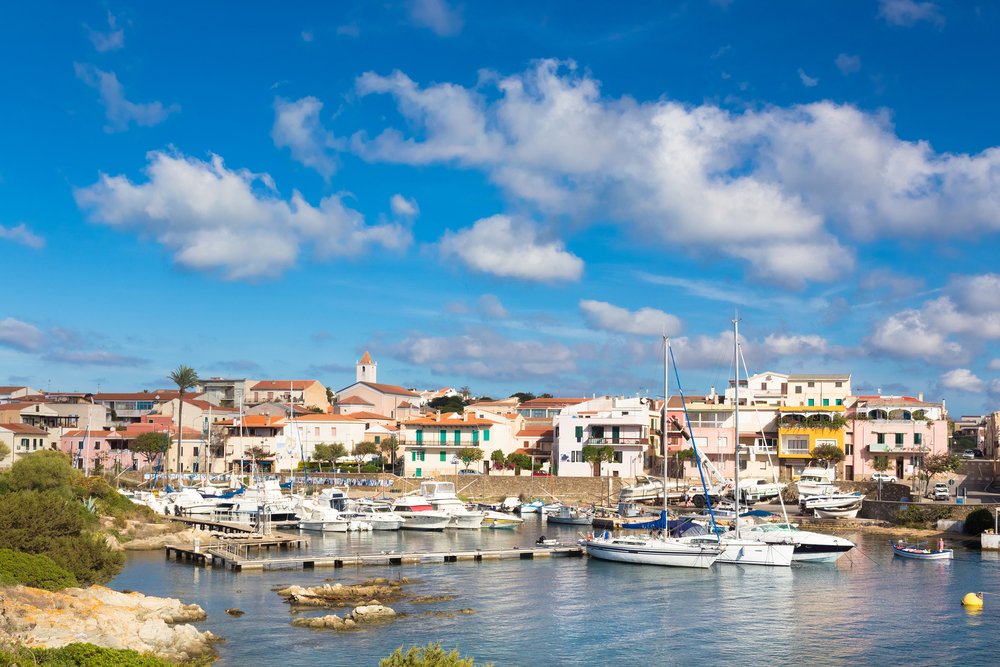 Picturesque old port town of Stintino, Sardinia, with boats in the harbor and colorful houses on the land