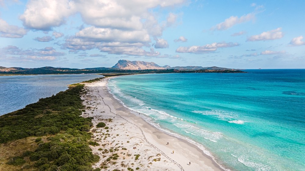 The famous La Cinta beach overlooking the island of Tavolara, with white sandy beach and soft blue water, broken into two parts by the beach