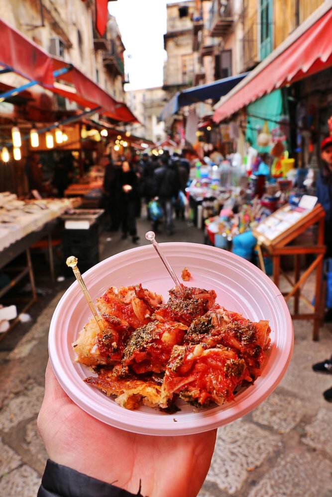 Person's hand holding a delicious plate of Sicilian street food purchased from a local market