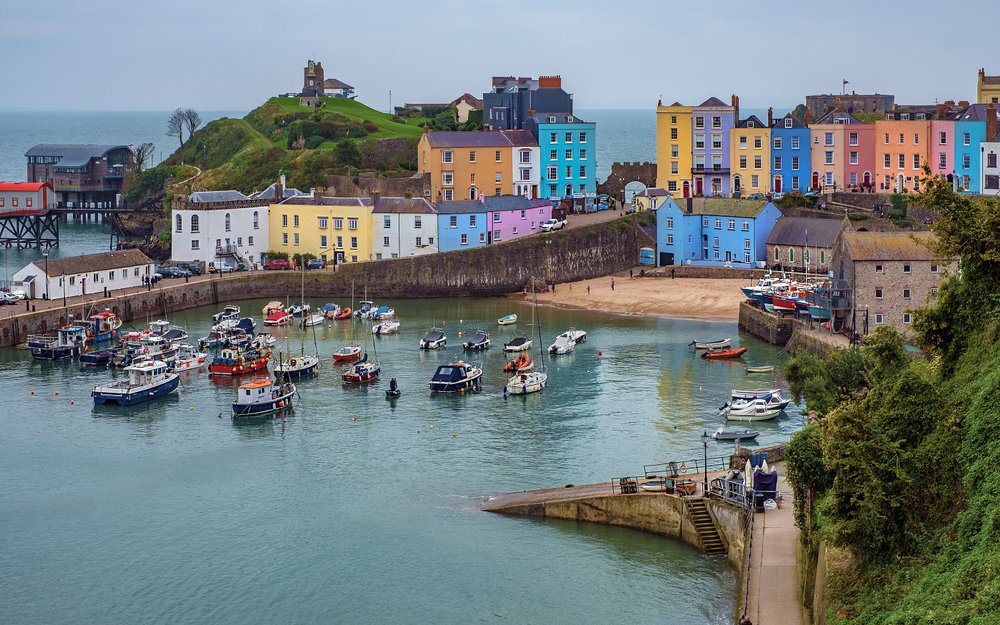 Colorful harbor houses in Tenby, Wales with small beach and lots of boats