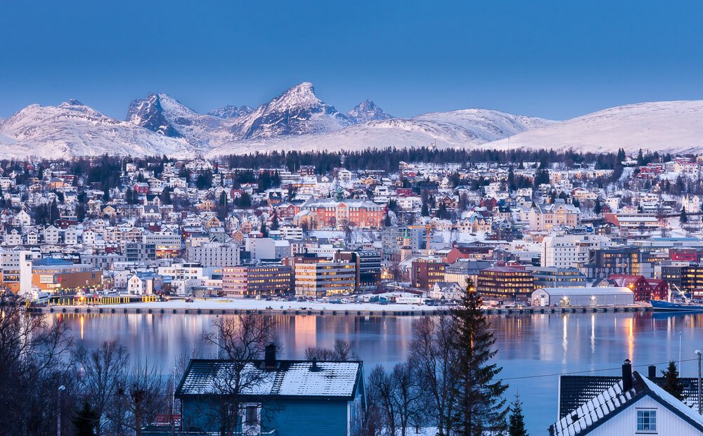 winter landscape of the city of tromso as seen at night when the lights in the city start to twinkle on and change the city into its night scene