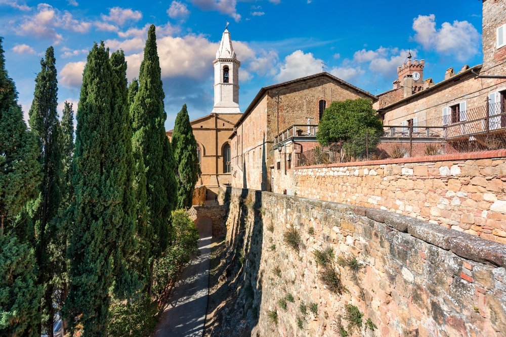 The charming hillside town of Pienza with stone walls, stone architecture, church steeples, cypress trees