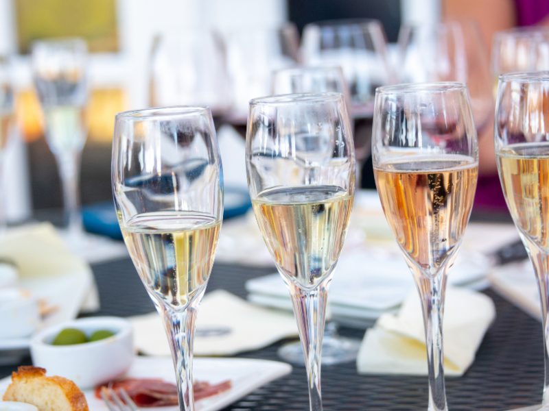 four glasses of champagne in champagne flutes with tasting snacks behind them