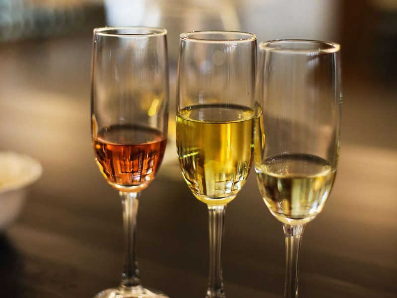 View of three champagne flutes, one with pink rose sparking wine, the others with white sparkling wine