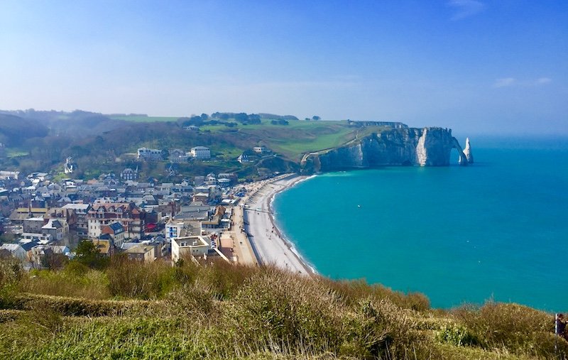 Brilliant turquoise water and sandy beach located next to bright white cliffs similar to the cliffs of dover, with a town alongside the water