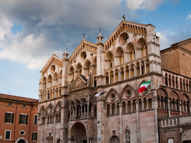 The ancient stone facade of Ferrara Cathedral in Italy, a scenic city with old architecture and lots of historic landmarks.