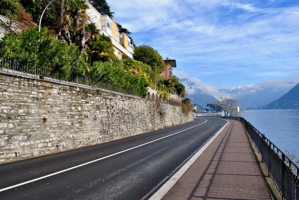 road along Lake Como, winding along the lakefront with beautiful lake views and historic homes and buildings next to the roadside