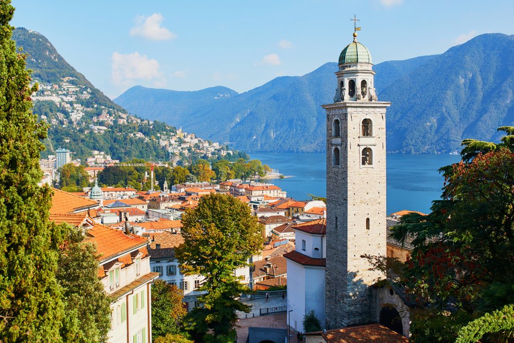 The old town of Lugano in Switzerland with view of Lake Como and mountains behind it and steeple of church
