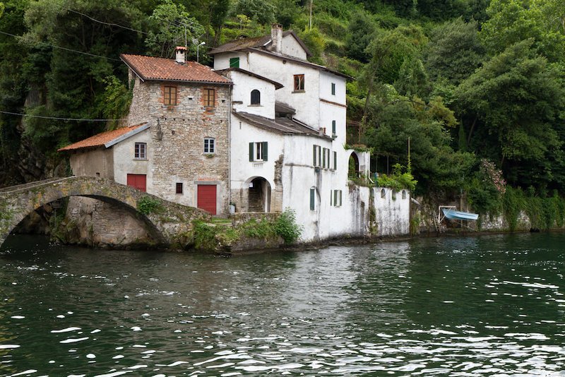 Old villas and houses in Nesso village at lake Como, Italy, with a small stone bridge crossing an inlet of the lake