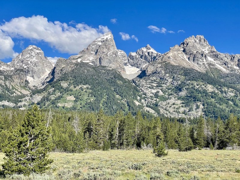 Beautiful landscape of Grand Teton National Park in the summer, with lots of trees and tall mountains that are part of the Teton Range in Wyoming
