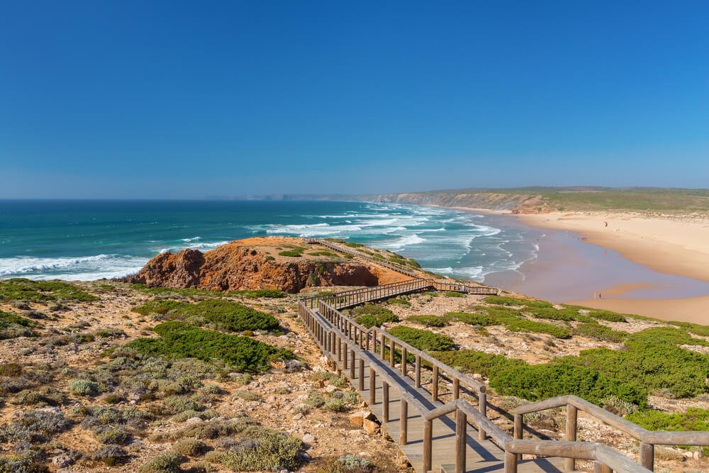 Wooden walkway to the beach Praia da Amoreira, District Aljezur, with stunning spread of sandy area with waves washing in from the ocean