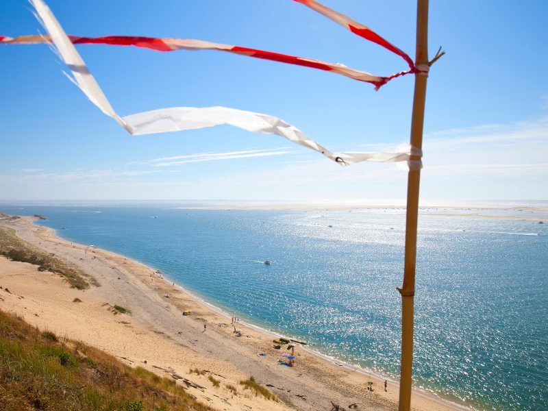 Stick with flying streamers and sandy beach below the sand dunes, with brilliant clear blue water