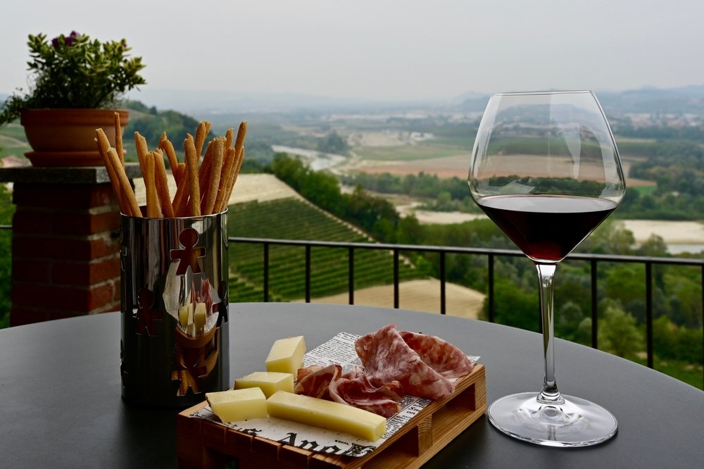 Aperitivo in the Barolo region. Glass of Barolo wine, some local cheese and meats and some breadsticks.
