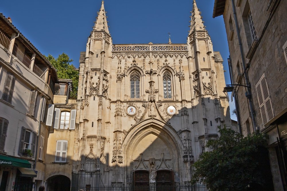 facade of the Basilique Saint Pierre church with an arch, twin windows, twin inlay circle portrait-type details, and twin spires on a sunny day.