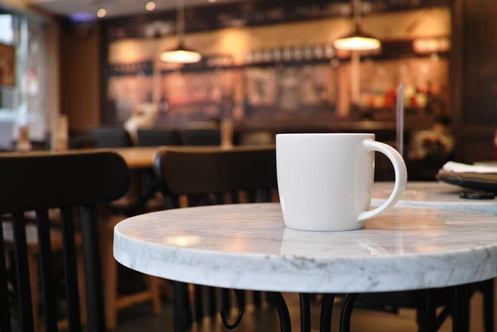 closeup of a cup of coffee at coffee shop, with blurred background