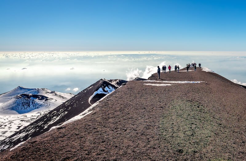 the summit of mt etna with some snow in the background on the top of the volcanic crater, part of an etna wine tour