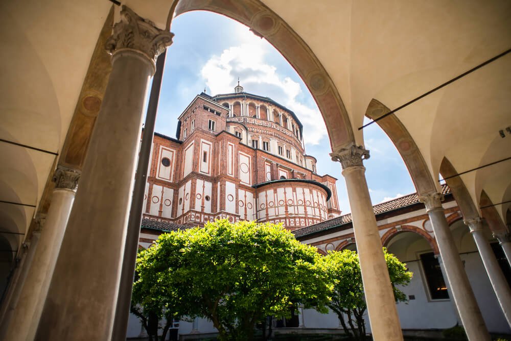 view of the circular side of the santa maria delle grazie convent seen through courtyard archways and the building seen between the arch's negative space