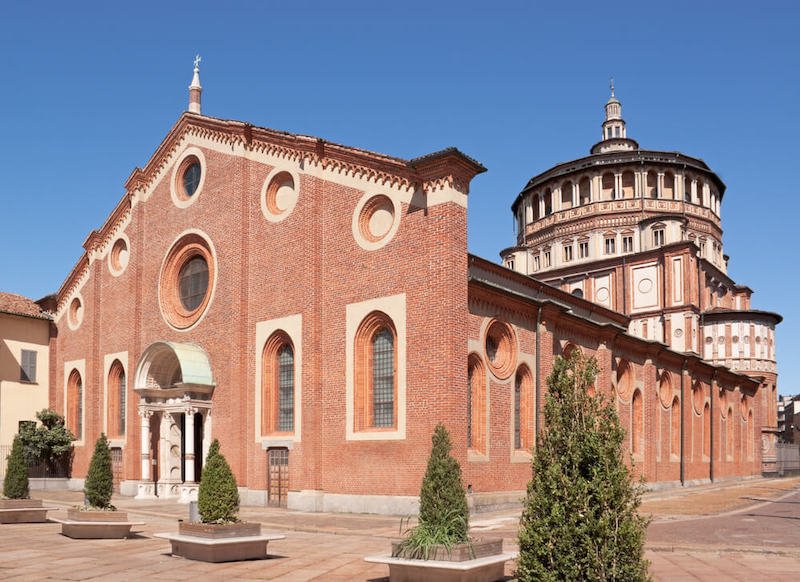 Santa Maria delle Grazie in Milan, Italy, with a red brick facade and a rounded building in the other side. This church and the adjacent Dominican convent were built during the 15th century. The back wall of the convent dining hall is covered by "The Last Supper"