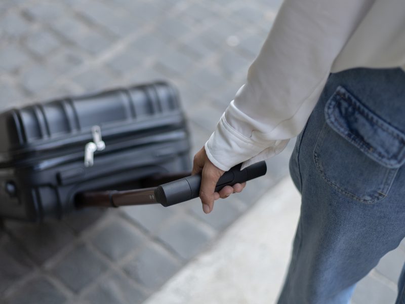 woman holding luggage on a street wearing a white shirt and jeans