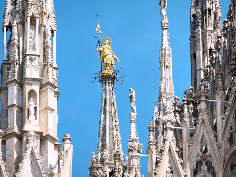 the golden madonnina statuette figure atop the milan duomo, a famous sign of the city