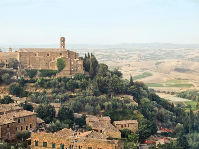 the hilltop town of montalcino in tuscany with scenic foothills and vineyards off in the distance in tuscany wine country