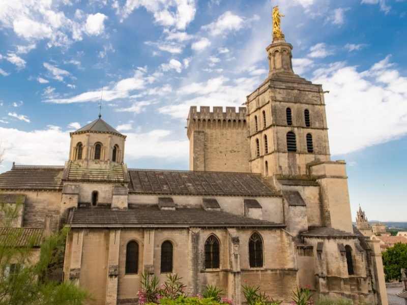 A side view of the avignon cathedral next to the palace of the popes