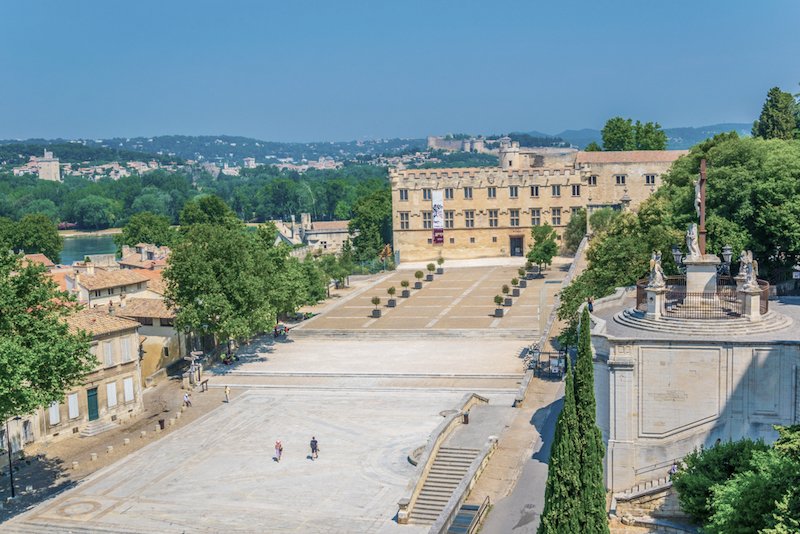 A view of the 'petit palais' which isn't as small as it sounds, which is now a musuem housing middle age and renaissance art, on a clear day with a few people walking towards the museum