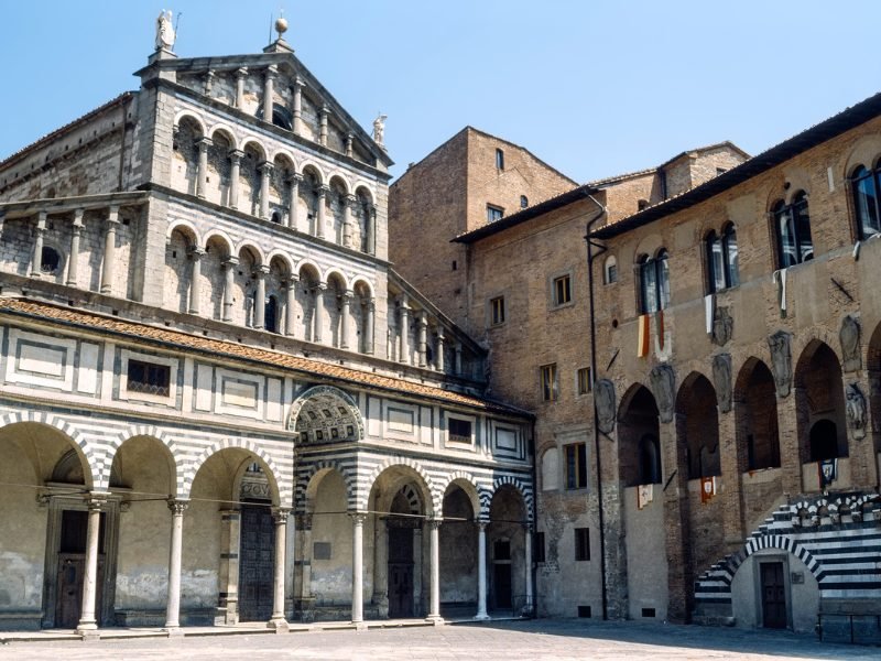 the medieval striped facade of the church in pistoia next to a plain brick building in the center of this charming town that was a capital of culture.