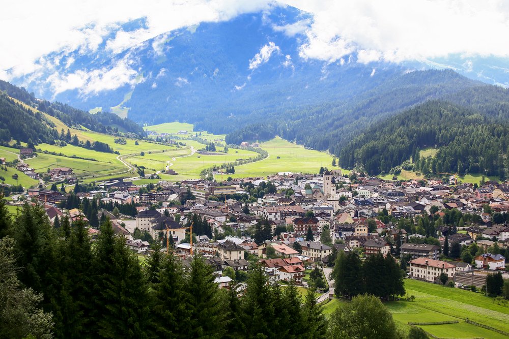 small town in the center of a valley surrounded by pine-covered mountains and misty sky