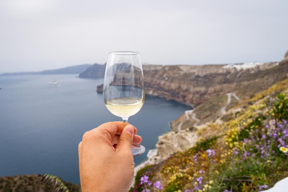 hand holding a glass of wine in the santorini landscape
