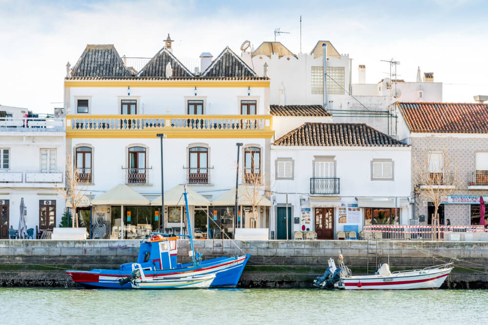Charming architecture of Tavira with boats on Gilao river, Algarve, Portugal, with yellow and azulejo tile style facades