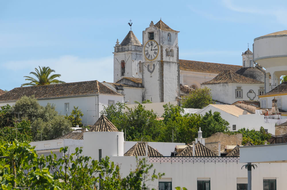 View of the historic center of the city of Tavira with the clock tower of the church of Santa Maria do Castelo, white-washed houses all around in this charming algarve town