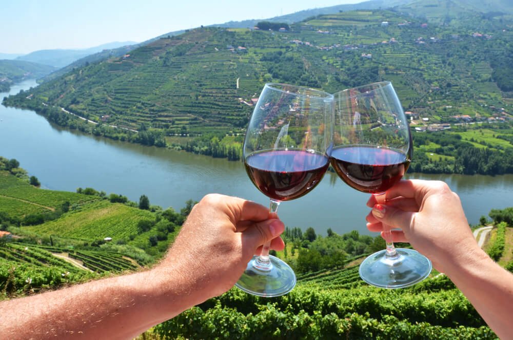 Two people doing the cheers movement in the Douro River valley while trying local wines