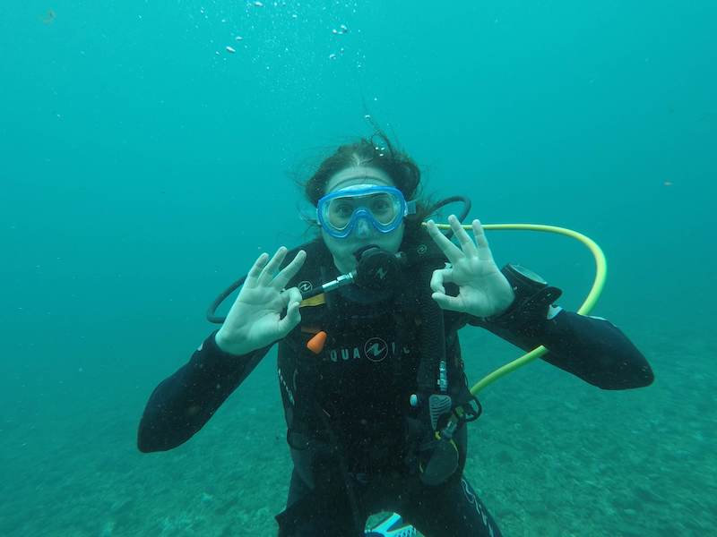 Allison Green underwater holding up two "OK" signs for scuba diving signals