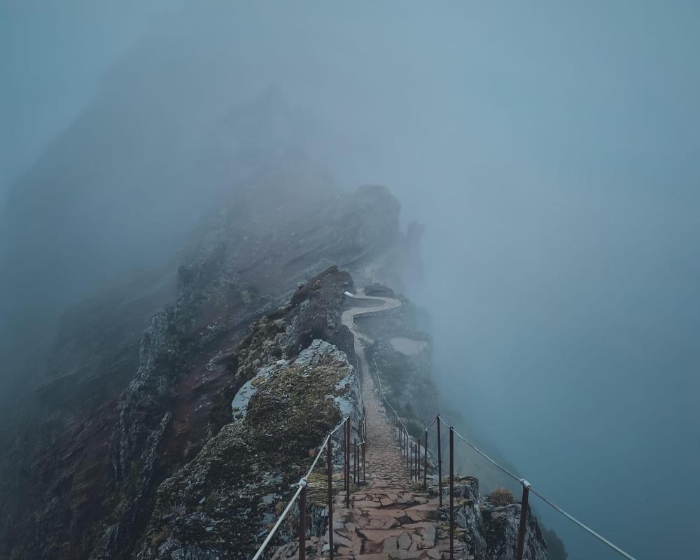 Photo from the top of Pico Ruivo with mist and handrails protecting hikers from falling