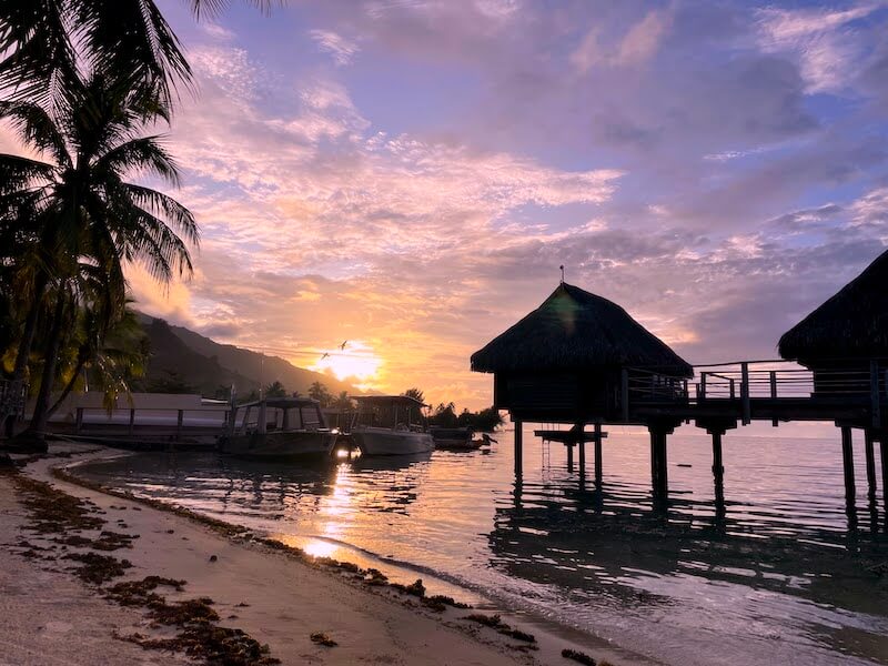 view of moorea sunset with brilliant colors and overwater bungalows forming a silhouette