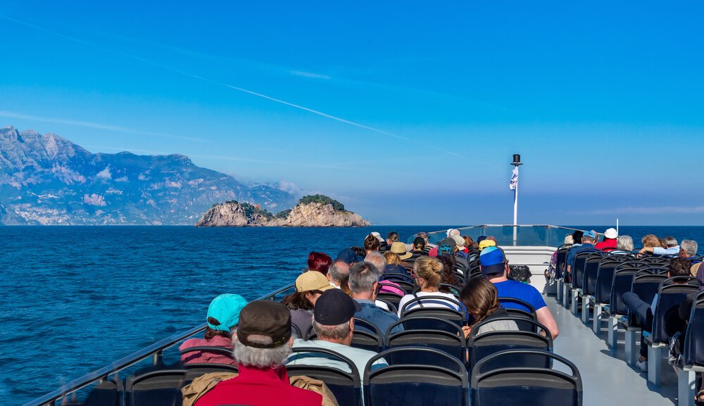 boat on the amalfi coast with people heading towards the coast line from capri