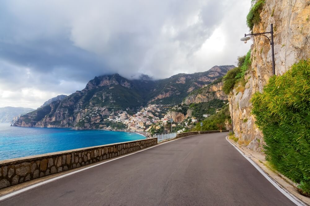 Scenic Road on Rocky Cliffs and Mountain Landscape by the Tyrrhenian Sea of the Amalfi coast, with the town of Positano in the background, on an overcast day in the spring or fall