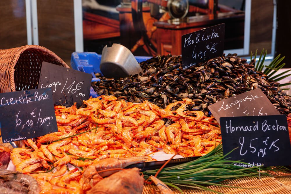 seafood like mussels and shrimp with words in french labeling it with prices