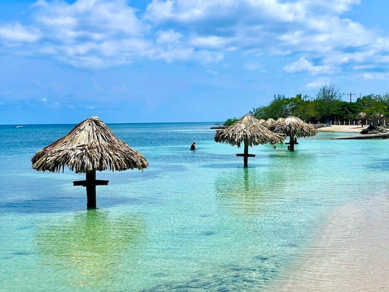 the lovely waters of chepes beach with palapas in the water with little shelves for holding drinks or snacks