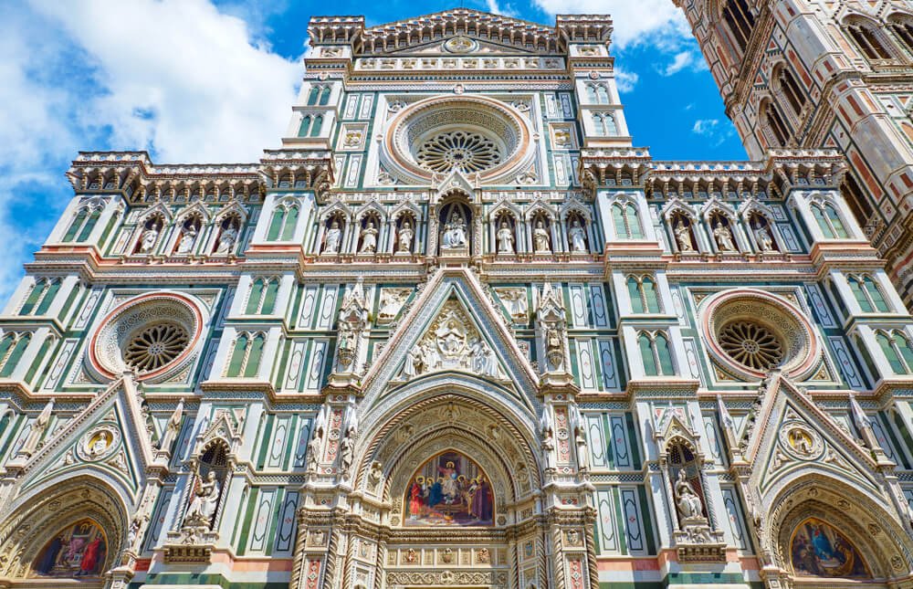 the facade of the florence duomo church with green marble and all sorts of detail work including mosaic