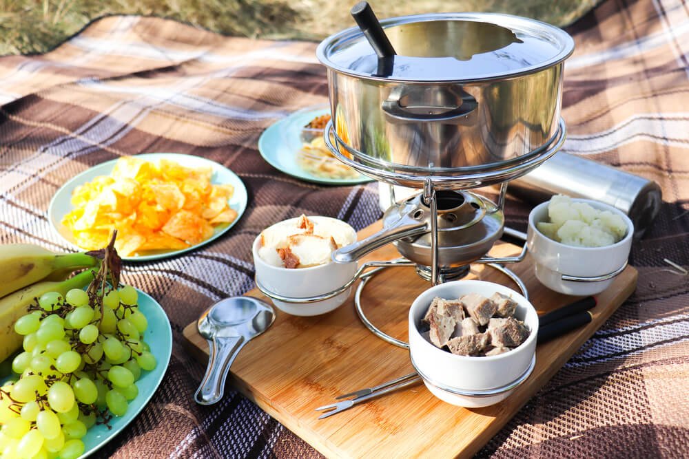 a picnic fondue set with cheese, bread, and grapes