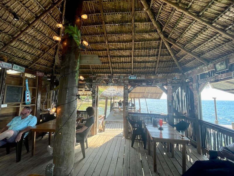 the bar area and restaurant of la sirena on the water in camp bay, roatan on a sunny day